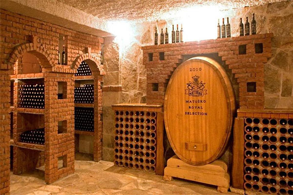 Large oak barrel and wine racks inside a stone wine cellar