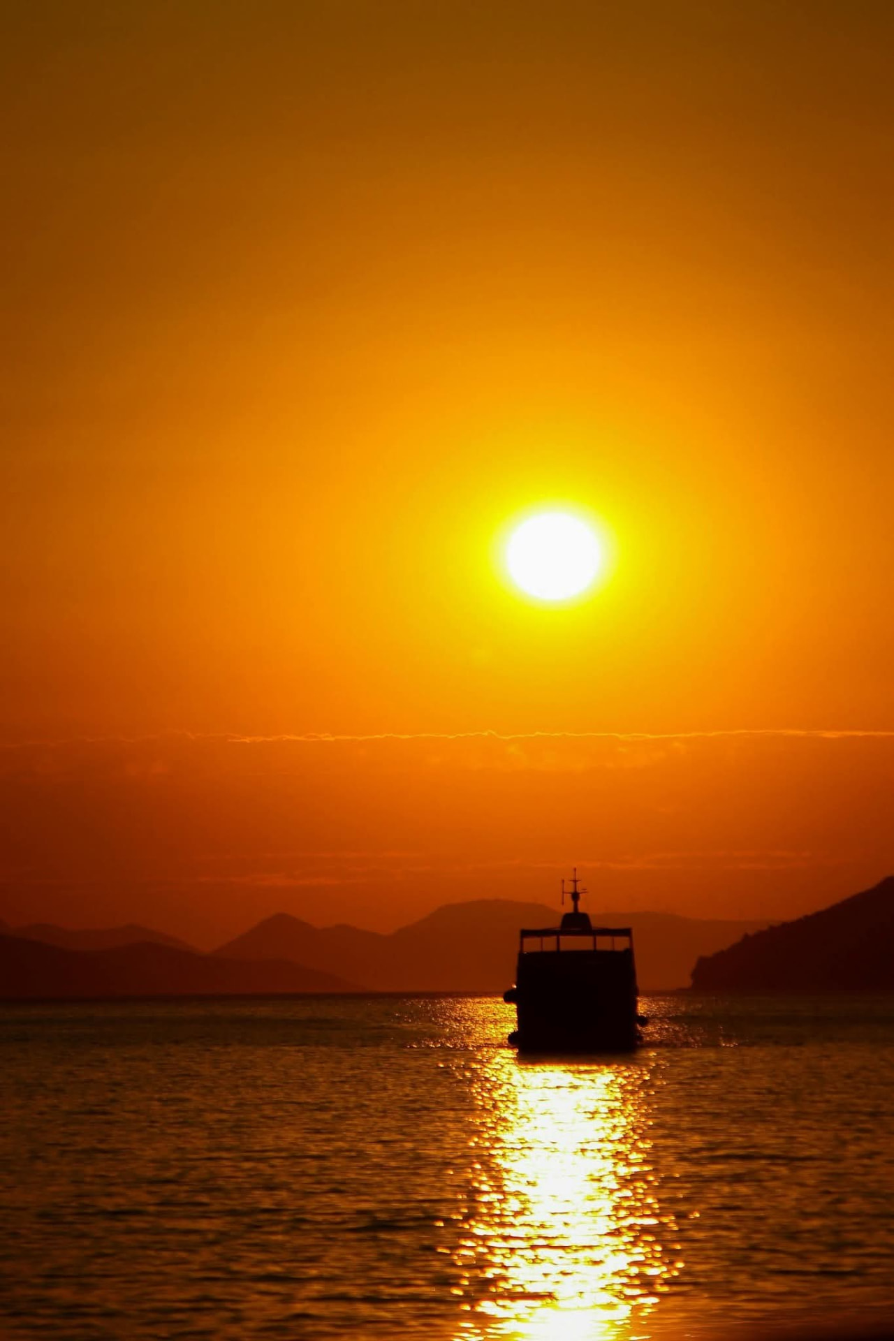 Silhouette of a boat on the sea against an orange Adriatic sunset