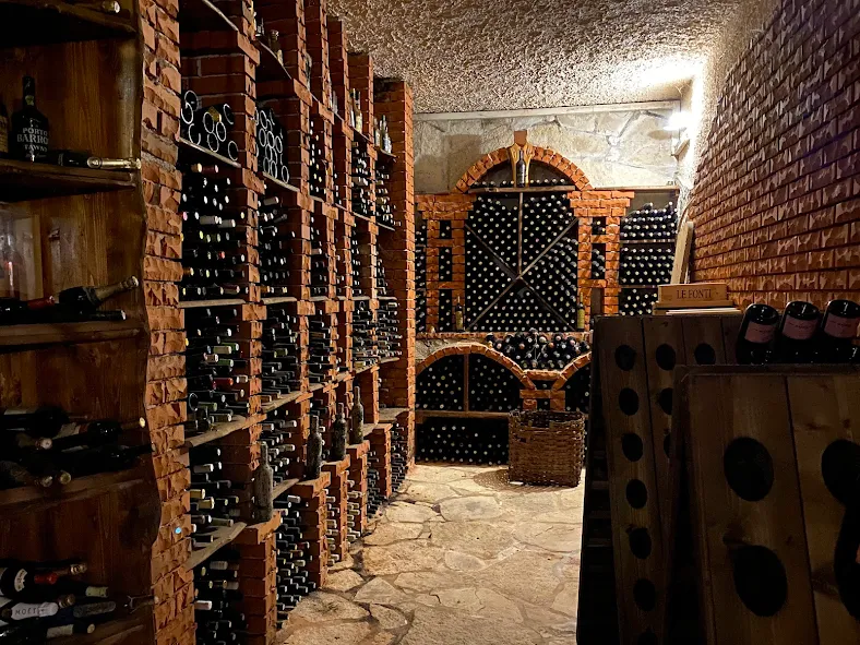 Stone wine cellar with rows of dusty bottles