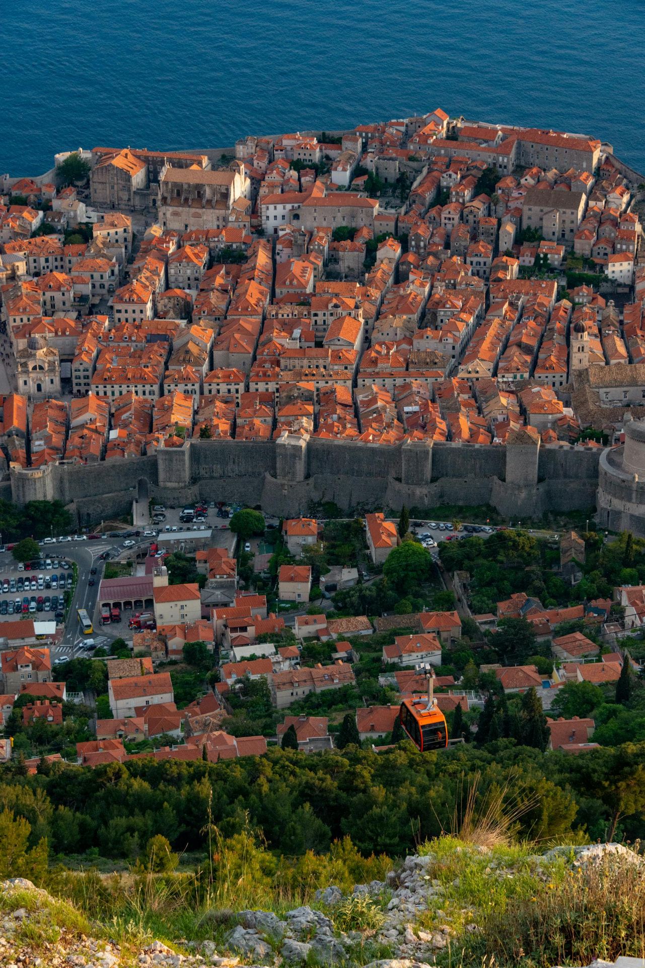Dubrovnik Old Town rooftops and city walls with an orange cable car cabin below