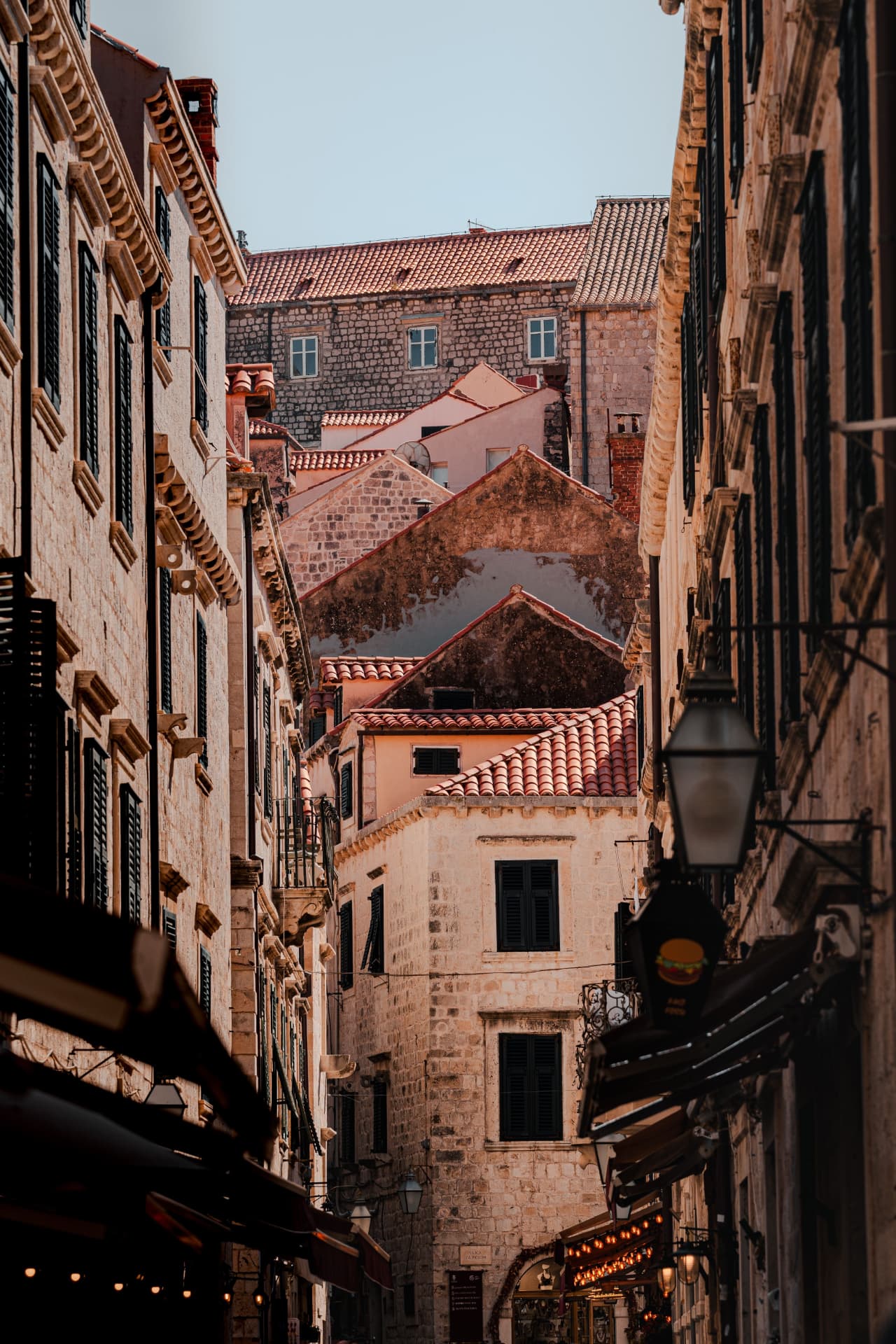 Narrow Dubrovnik lane between old stone houses with shutters and a street lantern
