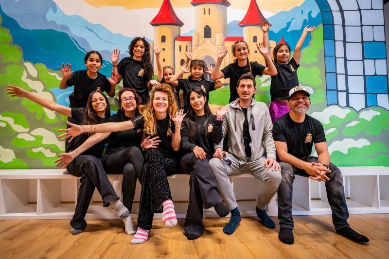 The Adventure Kingdom team and children in front of the castle mural