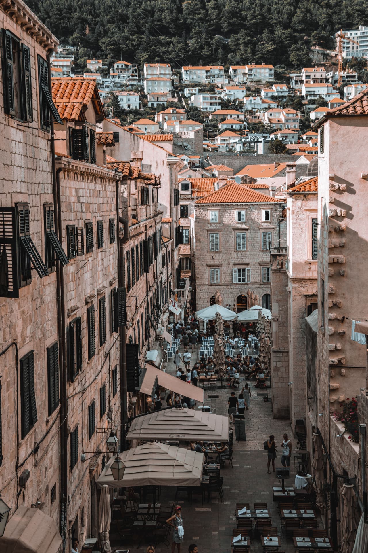 View from the city walls down a narrow Dubrovnik street lined with restaurant tables