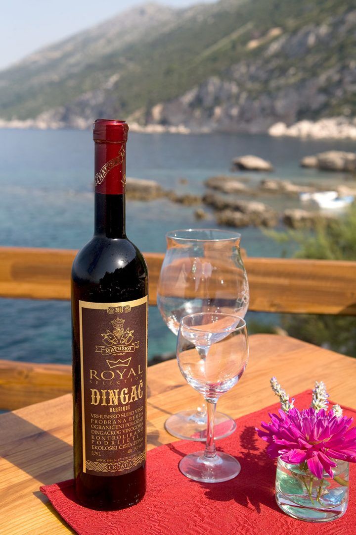 Bottle of Dingač red wine and glasses on a terrace above the sea